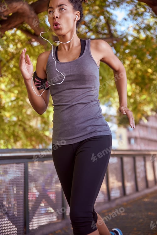 Preview: Young Woman Running In The Park While Listening To Music With Her Earphones On And Wearing Exercise
