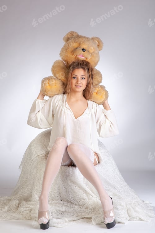 Preview: Young Beautiful Girl Posing With A Teddy Bear Sitting In A Chair In White Clothes