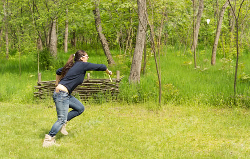 Preview: Athletic Woman Playing Badminton On A Grassy Rural Field Sprinting To Hit The Shuttle Cock As She