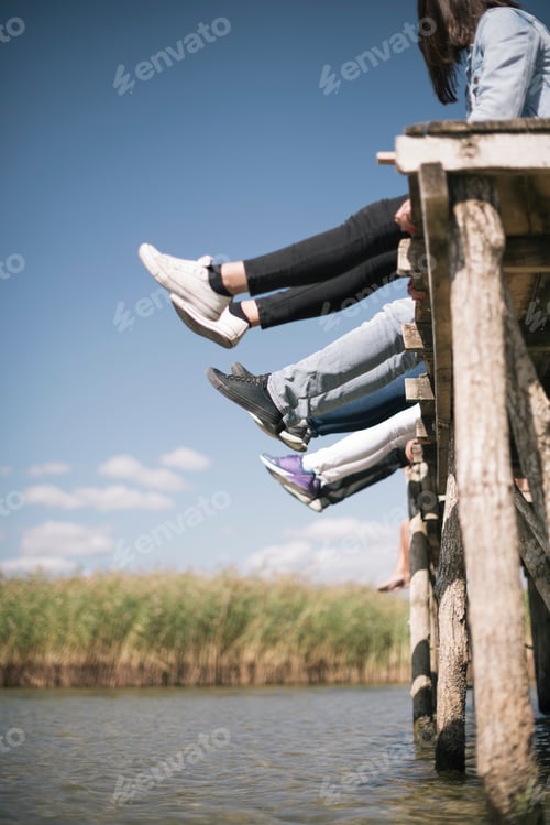 Preview: Couple Of Friends Relaxing On The Pear By A Lake. Summer Vacation Concept