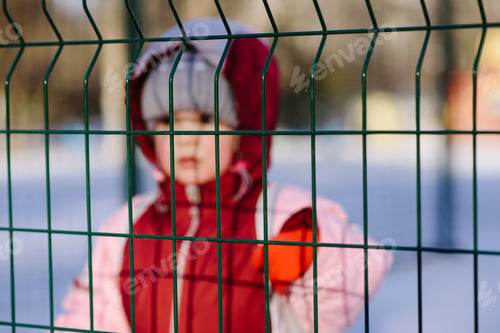 Preview: Little Kid Looks Through The Bars In Winter In The Park