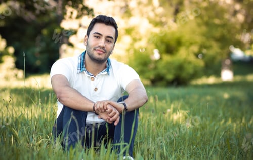 Preview: Man Sitting On Grass In Forest. Happy Guy Relaxing On Meadow. Daylight, Outdoors
