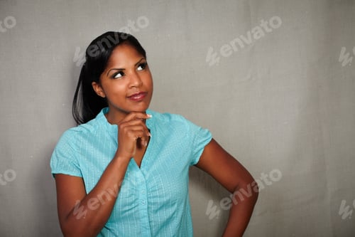 Preview: Charismatic Girl Planning With One Hand On Her Chin While Looking Away Against Grey Background