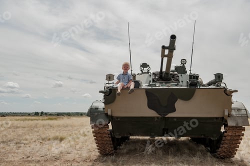 Preview: Child In Plaid Shirt With Toy Helicopter Climbed Onto Modern Battle Tank. Boy Is Crying. Concept Of