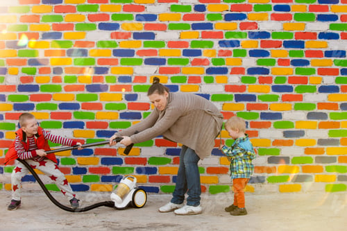 Preview: Happy Village Children And Their Slender Mother With Vacuum Cleaner Opposite The Multi-Colored