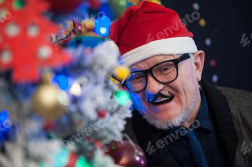 Preview: Elderly Man In Carnival Glasses With Gray Hair And Beard Next To Luminous And Blinking Christmas