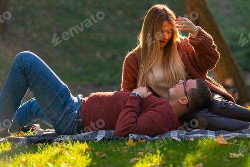Preview: Romantic Young Couple Relaxing On The Grass In A Park In Autumn In Golden Evening Light In A Close