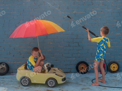 Preview: Funny Children In Boys' Bathing Suits Posing In Front Of Camera With High-Pressure Car Wash And Toy