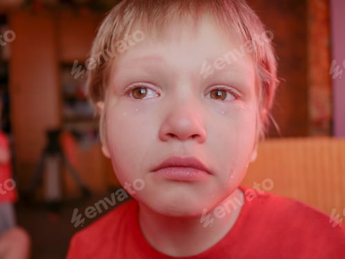 Preview: Upset Child In Red Sweater On Red Background Is Crying And Actively Expresses Emotions. Close Up