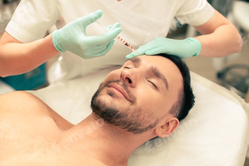 Preview: Close Up Of The Calm Young Man Lying With His Eyes Closed And Hands Of The Cosmetologist Touching