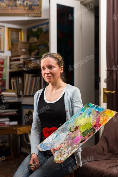 Preview: Female Holding A Colorful Artists Palette And Paintbrush In Her Hand In A Gallery