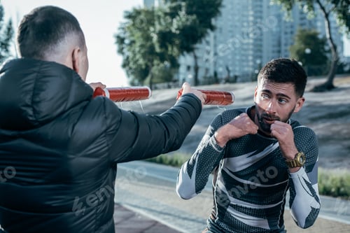 Preview: Attentive Professional Sportsman Looking At The Boxing Sticks While Having The Mma Training