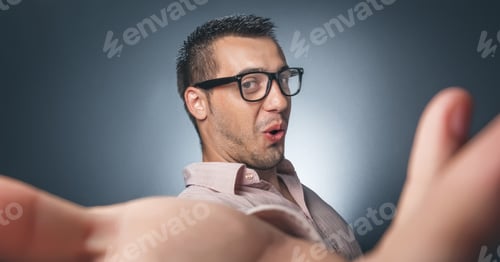 Preview: Selfie. Funny Young Man Taking A Selfie Photo Over Dark Gray Background. Studio Shot