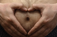 Vorschau: Lustiges Schwangerschaftskonzept. Mann hält eine herzförmige Hand auf seinem großen haarigen Bauch