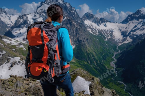 Preview: A Young Woman Tourist In A Blue Blouse With An Orange Hiking Backpack Enjoys A Breathtaking View Of
