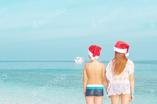 Preview: Children A Boy And A Girl In Swimsuits And Santa Hats Stand On The Shore Of Ocean In The Maldives