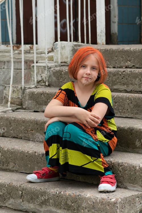 Preview: Little Girl With Red Hair Sits On The Steps Near The House