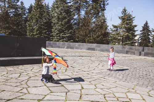 Preview: Two Little Girls Fun With Colorful Flying Kite In The Park At Spring Day