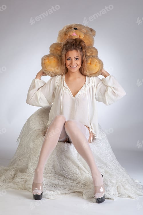 Preview: Young Beautiful Girl Posing With A Teddy Bear Sitting In A Chair In White Clothes