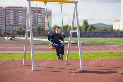 Preview: A Little Boy Swinging On A Swing On The Playground.