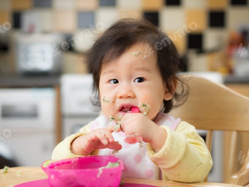 Preview: Asian Baby Girl Eating Vegetable At Home Kitchen