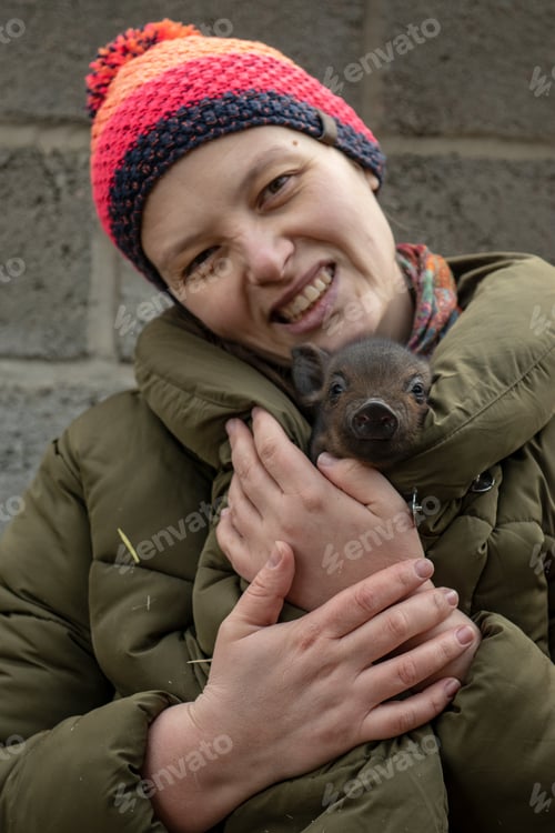 Preview: Happy Girl In Orange Hat Is Playing With Newborn Pigs. Winter Yard. Close-Up With Hands And Pigs