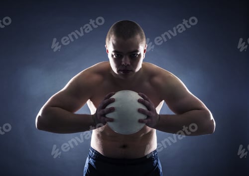 Preview: Muscular Athlete With The Ball On A Dark Background.