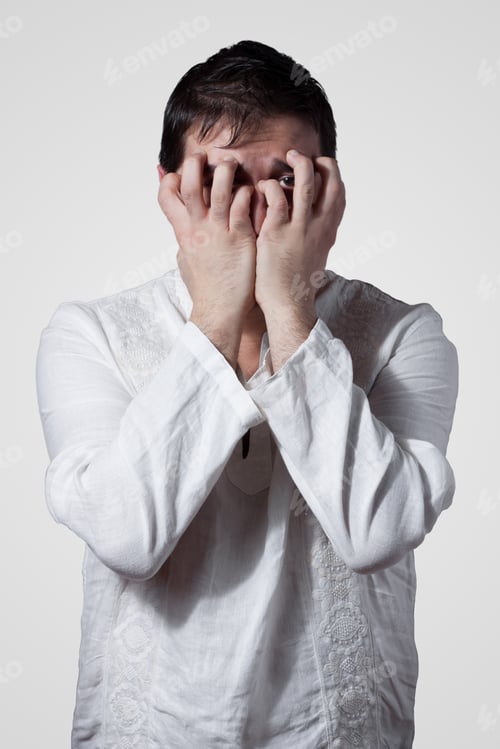 Preview: Young Man Hiding His Face With Hands While Looking Through Fingers