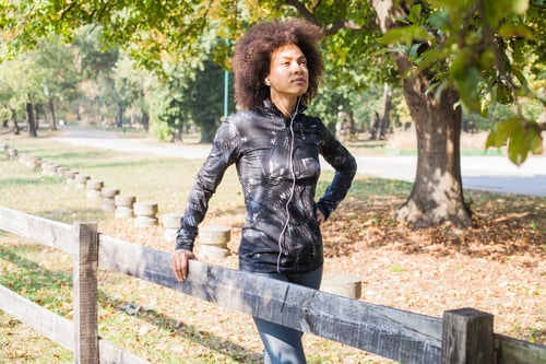 Preview: Attractive Sporty Woman Relax After Training Listening Music At Park, Leaning On Wooden Fence In