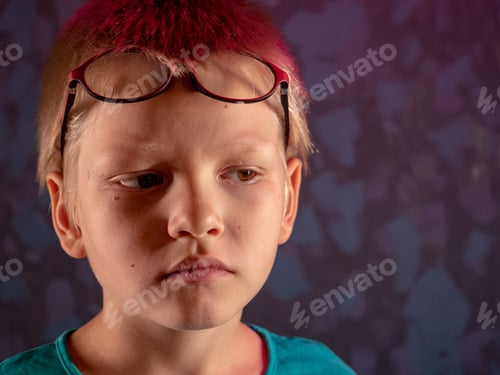 Preview: Cute Blond Child In Blue T-Shirt And Glasses Posing In Front Of Camera And Smiling