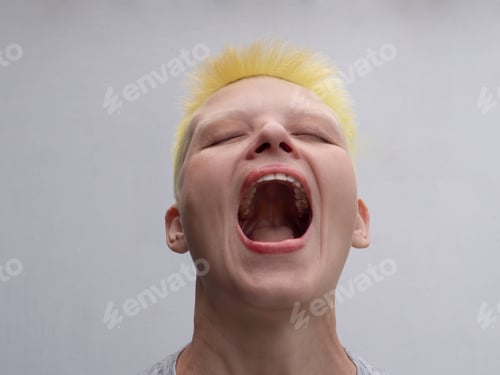 Preview: Middle Aged Woman With Yellow-Green Hair Laughs On White Background, Showing Perfect White Teeth
