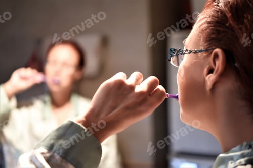 Preview: Beautiful Woman Brushing Teeth After Eating In Front Of A Mirror In The Bathroom.