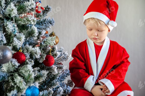 Preview: Cute Boy Dressed In Festive Costumes Of Santa Claus And Decorate Christmas Tree With Balls And