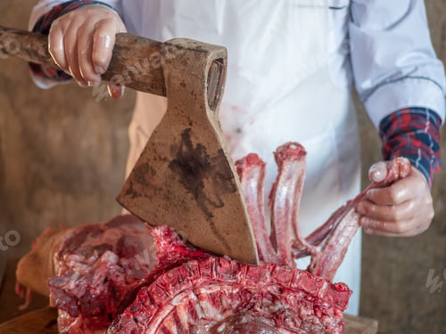 Preview: Elderly Man With A Gray Beard In Cook Suit And White Apron Cuts Into Pieces Large Piece Of Pork