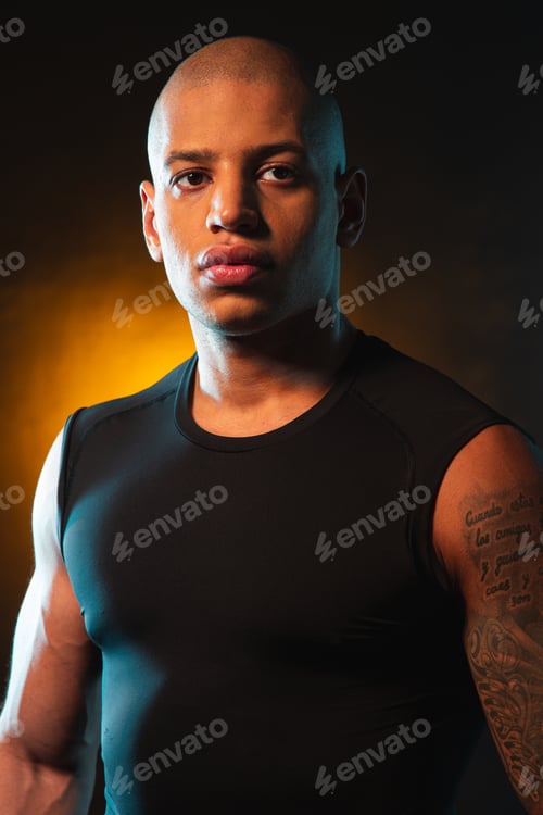 Preview: Serious Bold Sporty Man Standing On Orange Light Background And Thoughtfully Looking Away