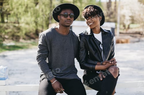 Preview: A Beautiful And Stylish Young African Couple In Sunglasses And Hats Embracing On A Outdoor Of Summer