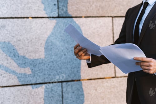 Preview: Close-Up Businessman In A Classic Suit Reading Advantageous Business Document In Paper Form