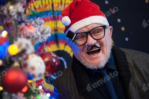 Preview: Elderly Man In Glasses With Gray Hair And Beard Next To Luminous And Blinking Christmas Lights