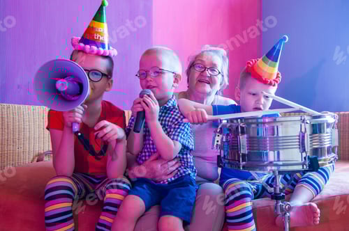 Preview: Elderly Woman In Pink T-Shirt And Glasses Holding Megaphone. Next To Grandmother, Grandchildren In