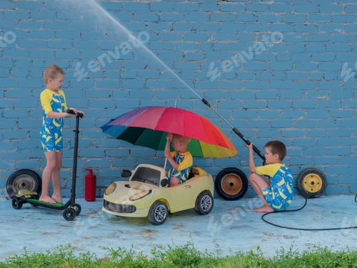 Preview: Funny Children In Boys' Bathing Suits Posing In Front Of Camera With High-Pressure Car Wash And Toy