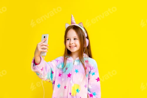 Preview: Little Girl In A Unicorn Costume Takes A Selfie. A Child In A Kigurumi Unicorn Smiles As He Speaks