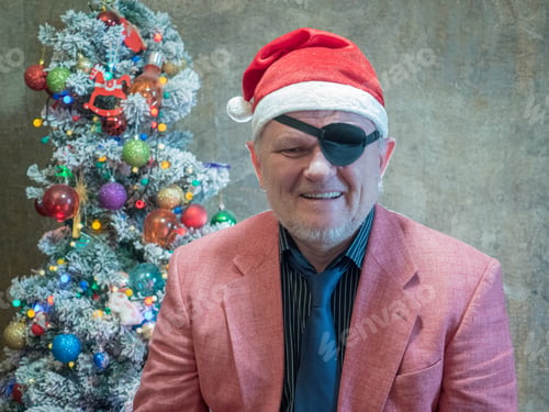 Preview: Elderly Hipster Man In Pink Jacket And Black Bandage Through One Eye Sits On Background Of