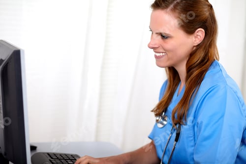 Preview: Portrait Of A Blonde Friendly Nurse Looking To Computer Screen At Workplace