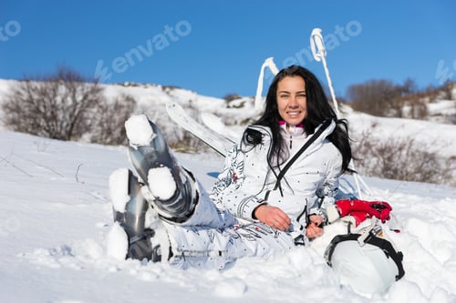 Preview: Full Length Of Contented Young Woman With Long Dark Hair Sitting With Legs Crossed On Snow Covered