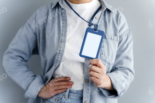 Preview: Young Caucasian Girl Showing Name Tag On Gray Background. Close View, Blank Name Tag.