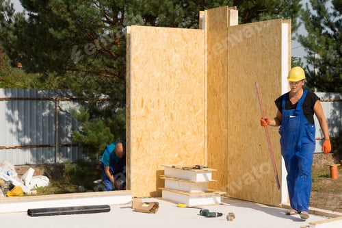 Preview: Workmen Busy Erecting Insulated Walls On A Construction Site Installing The Corner Units On The