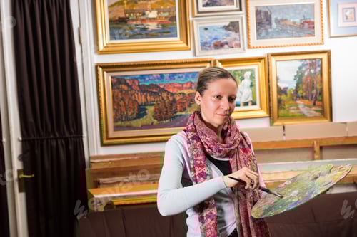 Preview: Professional Woman Artist Painting In A Studio Holding A Colorful Artists Palette And Paintbrush In