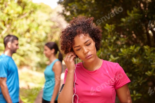 Preview: A Young Girl With A Pink T-Shirt Fitting An Earphone, While Her Friends Chat In The Background Out