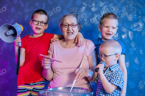 Preview: Elderly Woman In Pink T-Shirt And Glasses Holding Megaphone. Next To Grandmother, Grandchildren In