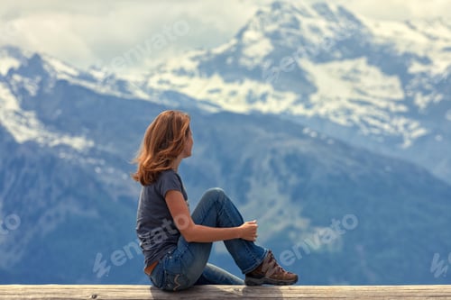 Preview: Girl Hiker Sitting And Looking At The Snowed Mountains